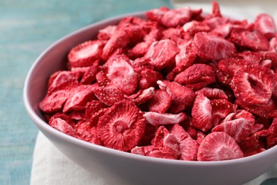 Photo of Bowl with dried strawberries on light blue table, closeup