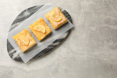 Photo of Tasty lemon bars on light grey table, top view. Space for text