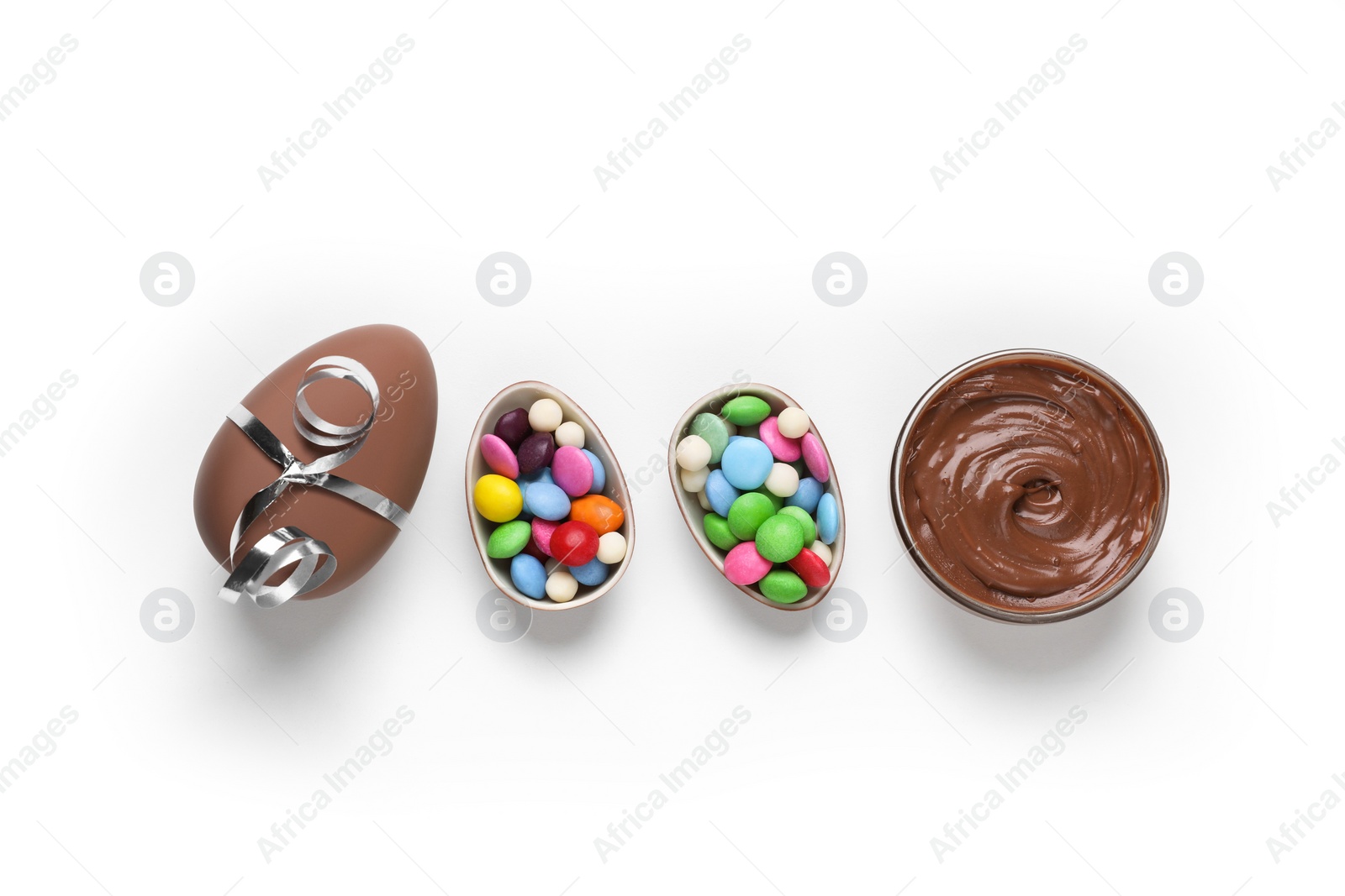 Photo of Delicious chocolate eggs, paste and colorful candies on white background, flat lay