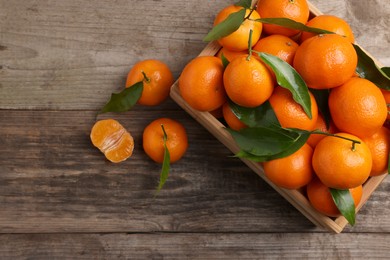 Photo of Delicious tangerines with leaves on wooden table, flat lay. Space for text