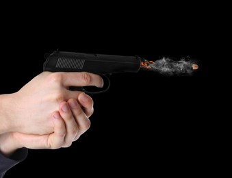 Image of Man shooting from gun on black background, closeup