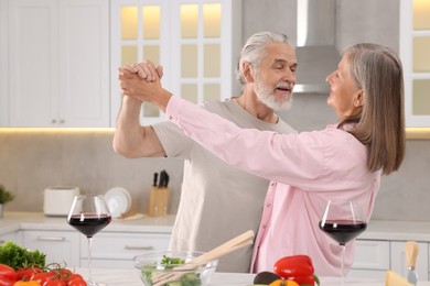 Photo of Happy affectionate senior couple dancing in kitchen