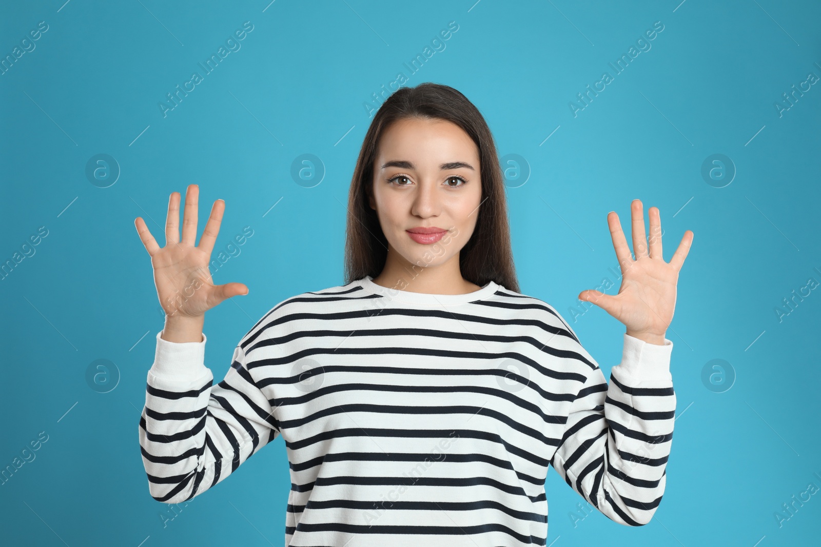 Photo of Woman showing number ten with her hands on light blue background