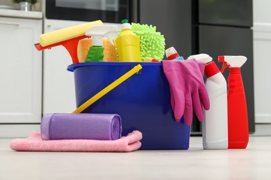 Different cleaning supplies in bucket on floor