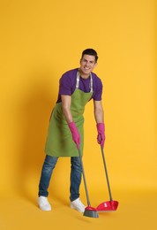 Photo of Man with broom and dustpan on orange background
