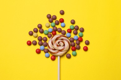 Delicious lollipop and candies on yellow background, flat lay