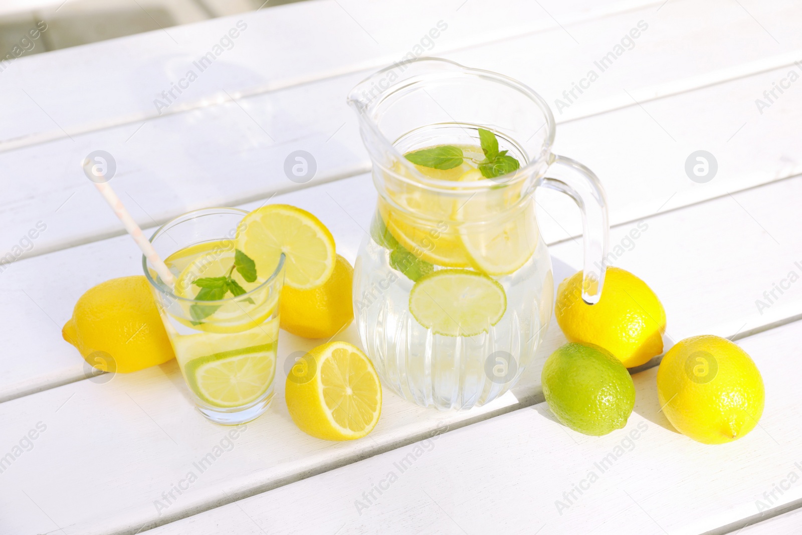 Photo of Water with lemons and limes on white wooden table outdoors