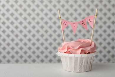 Photo of Delicious cupcake with pink cream and Girl topper on white table, space for text. Baby shower party