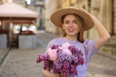 Photo of Beautiful woman with bouquet of spring flowers on city street, space for text