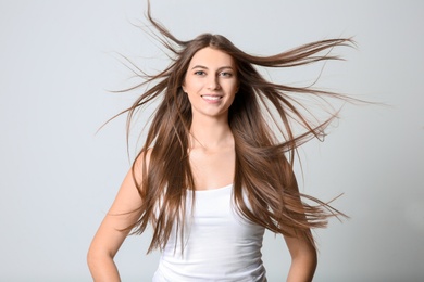 Portrait of young woman with long beautiful hair on light background