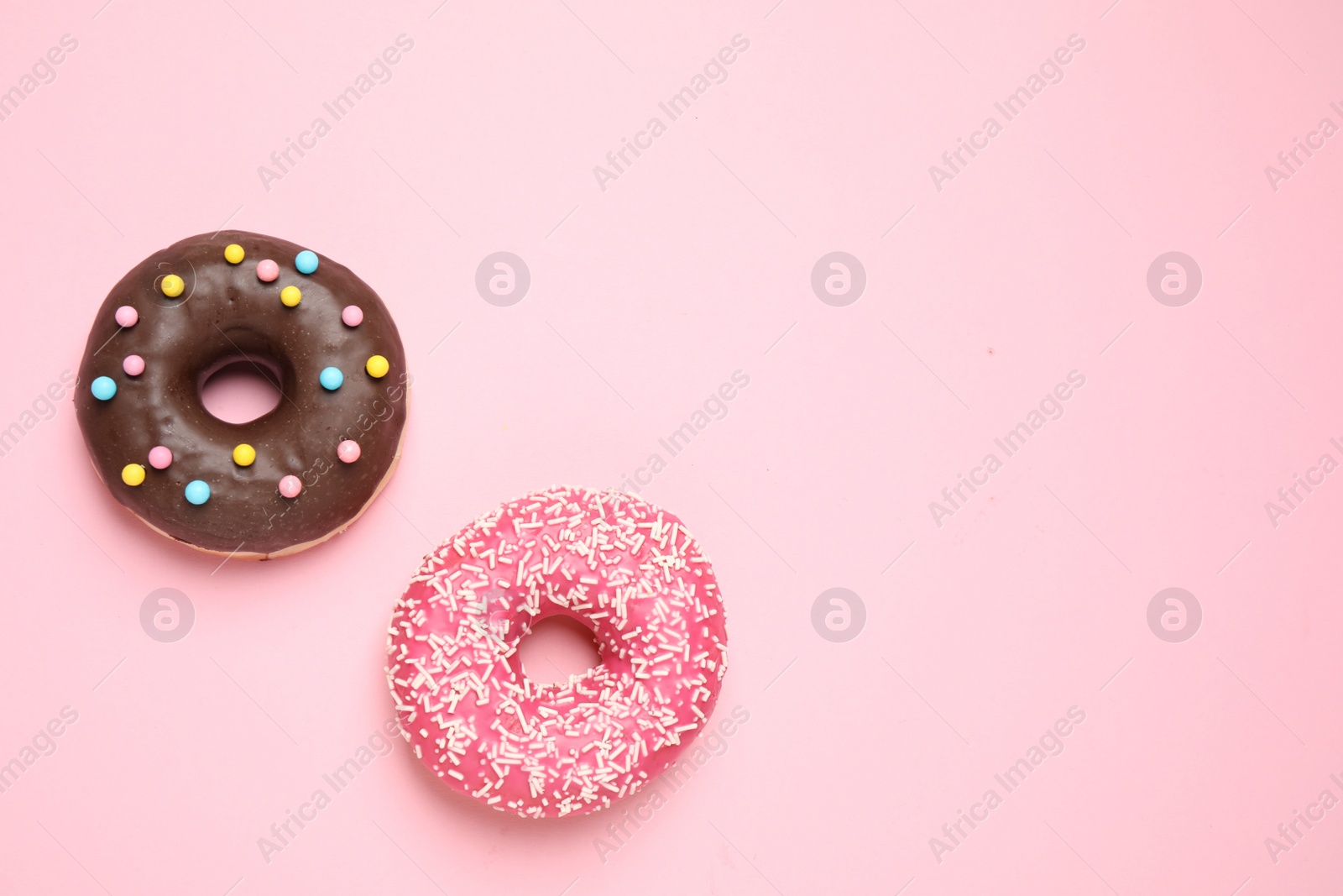 Photo of Delicious glazed donuts on pink background, flat lay. Space for text