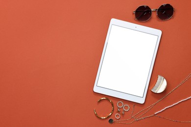 Photo of Modern tablet, sunglasses and bijouterie on color background, flat lay. Space for text
