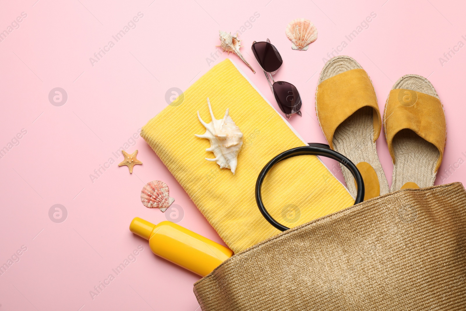 Photo of Stylish bag with beach accessories on pink background, flat lay