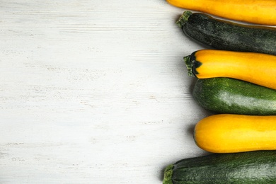 Fresh ripe zucchinis on white wooden table, flat lay. Space for text