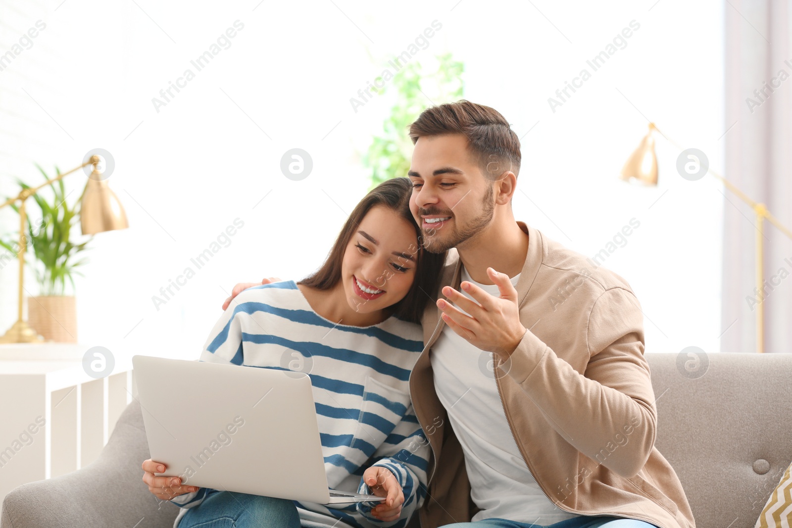 Photo of Couple using laptop for video chat in living room