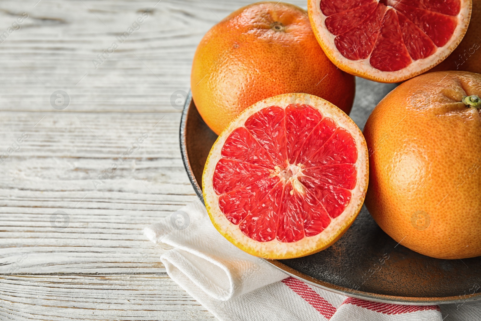 Photo of Plate of fresh grapefruits on table. Space for text