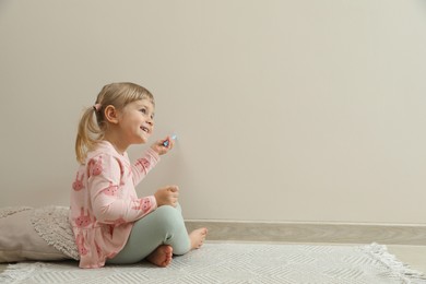 Photo of Little girl drawing on beige wall indoors, space for text. Child`s art