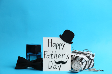 Photo of Card with phrase HAPPY FATHER'S DAY and male accessories on light blue background