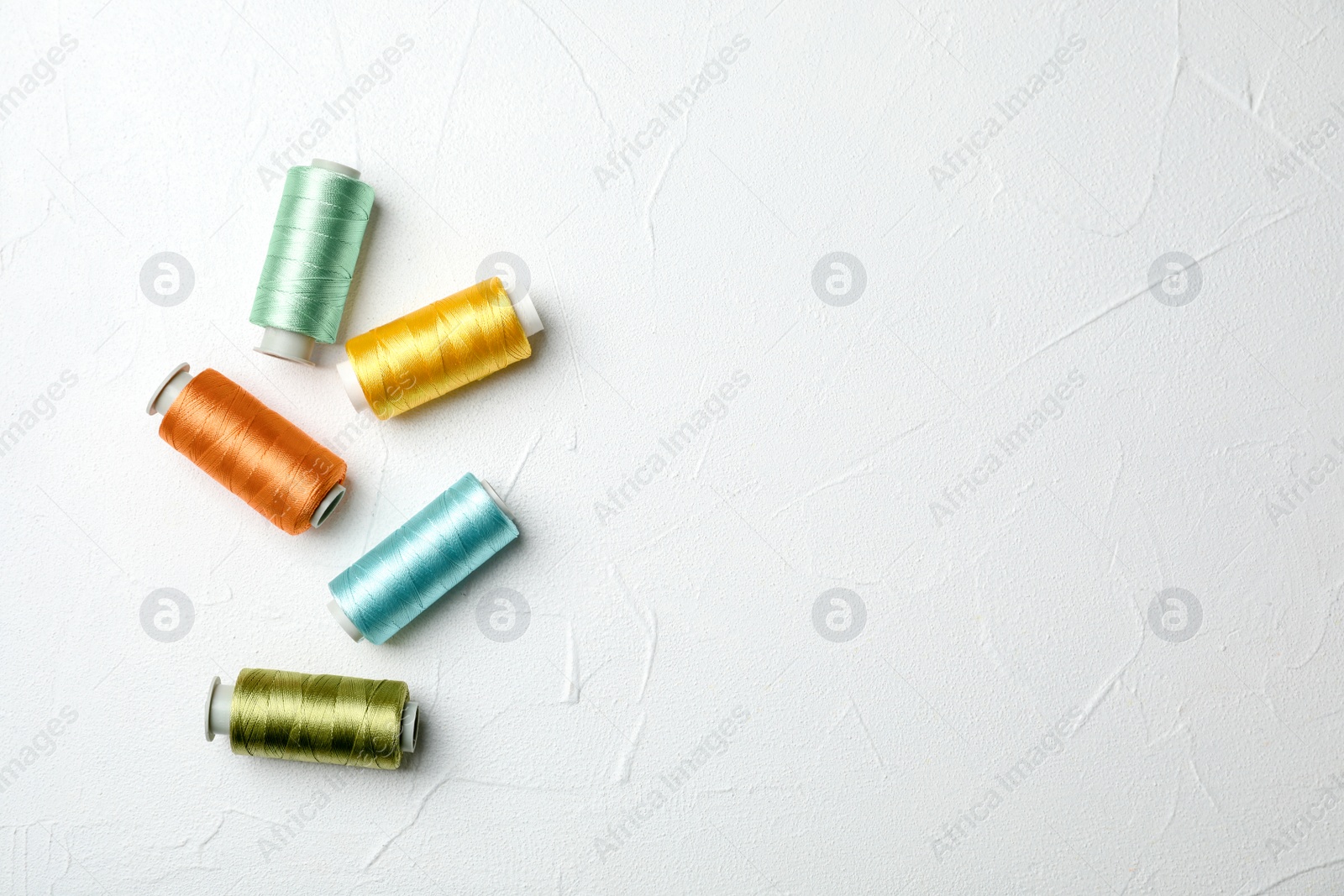 Photo of Color sewing threads on light background, top view