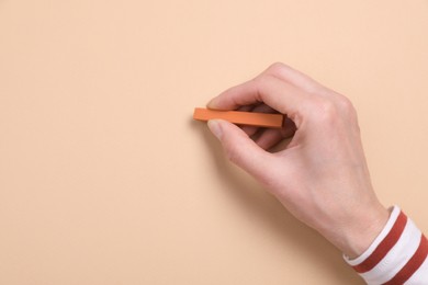 Photo of Woman drawing on beige paper with pastel, top view. Space for text