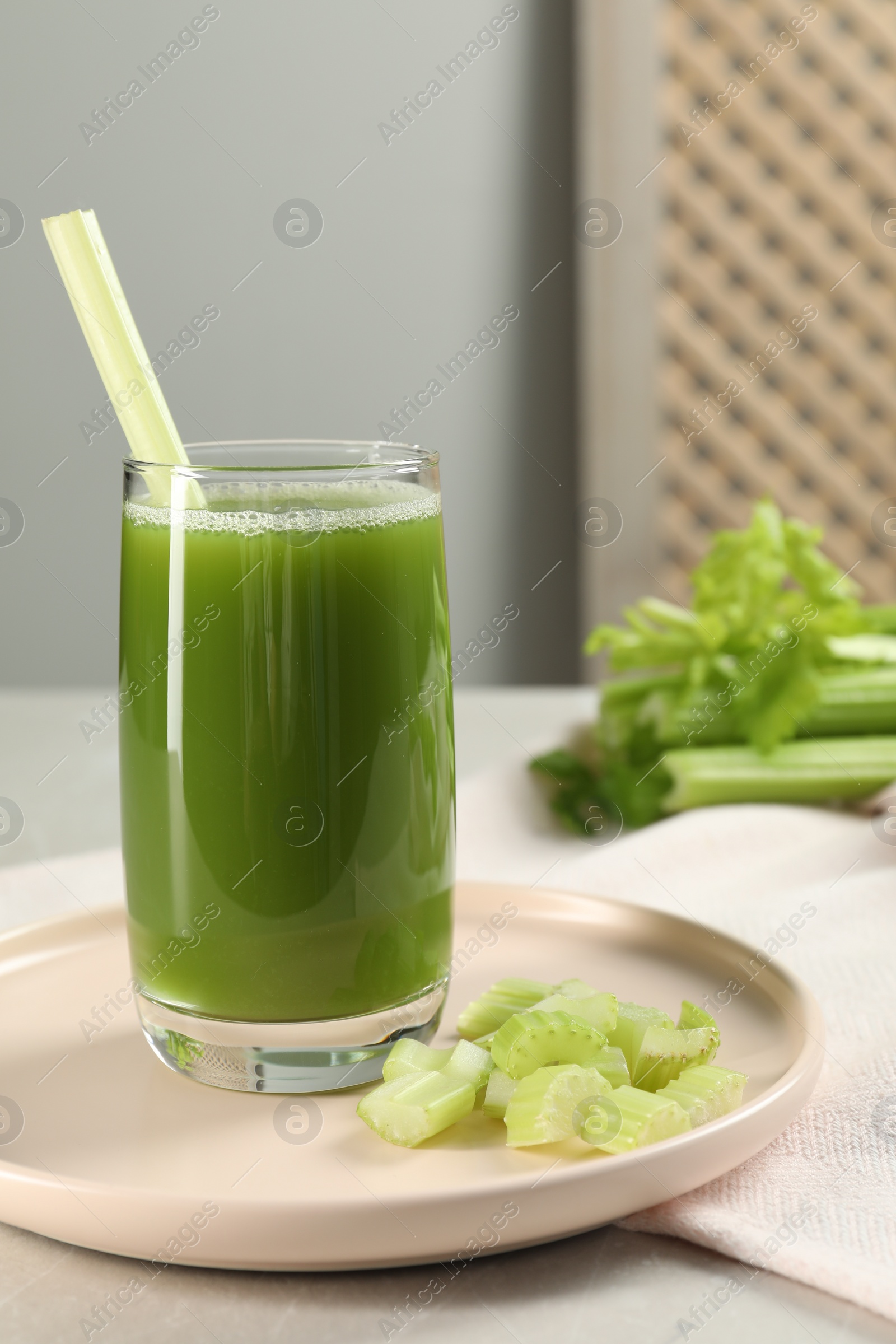Photo of Glass of delicious celery juice and vegetables on grey table, closeup