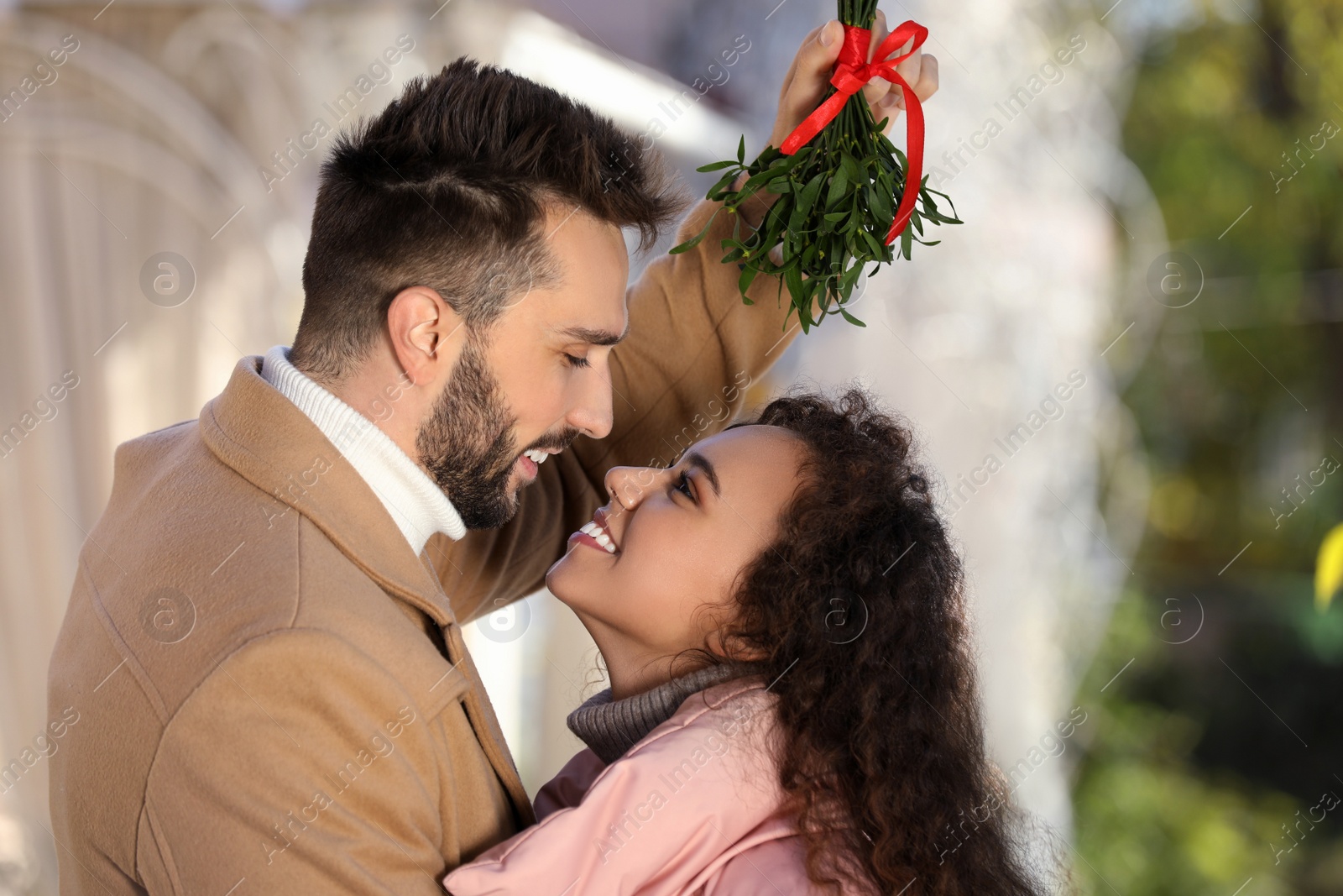 Photo of Happy couple under mistletoe bunch outdoors. Christmas tradition