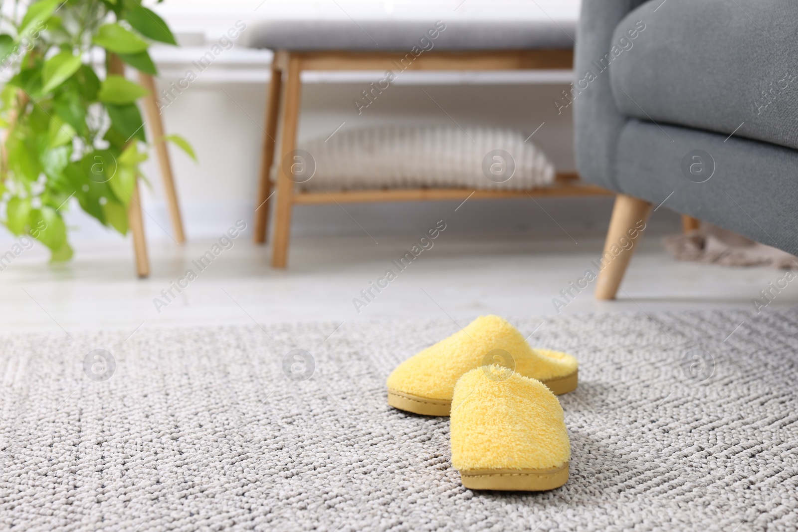 Photo of Yellow soft slippers on crochet carpet indoors. Space for text