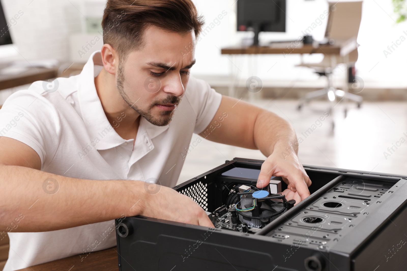 Photo of Male technician repairing computer at table indoors