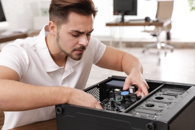 Male technician repairing computer at table indoors