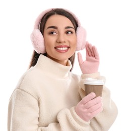 Beautiful young woman in earmuffs with cup of drink on white background