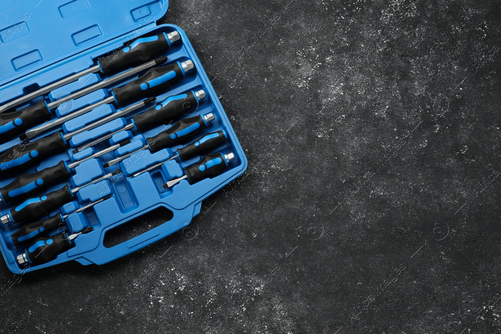 Photo of Set of screwdrivers in open toolbox on dark textured table, top view. Space for text