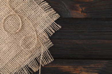 Photo of Thread and burlap fabric on wooden table, top view. Space for text