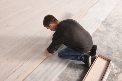 Professional worker installing new laminate flooring. Space for text