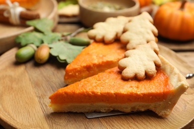 Slices of delicious homemade pumpkin pie on wooden plate, closeup