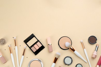 Different makeup brushes and cosmetic products on beige background, flat lay. Space for text