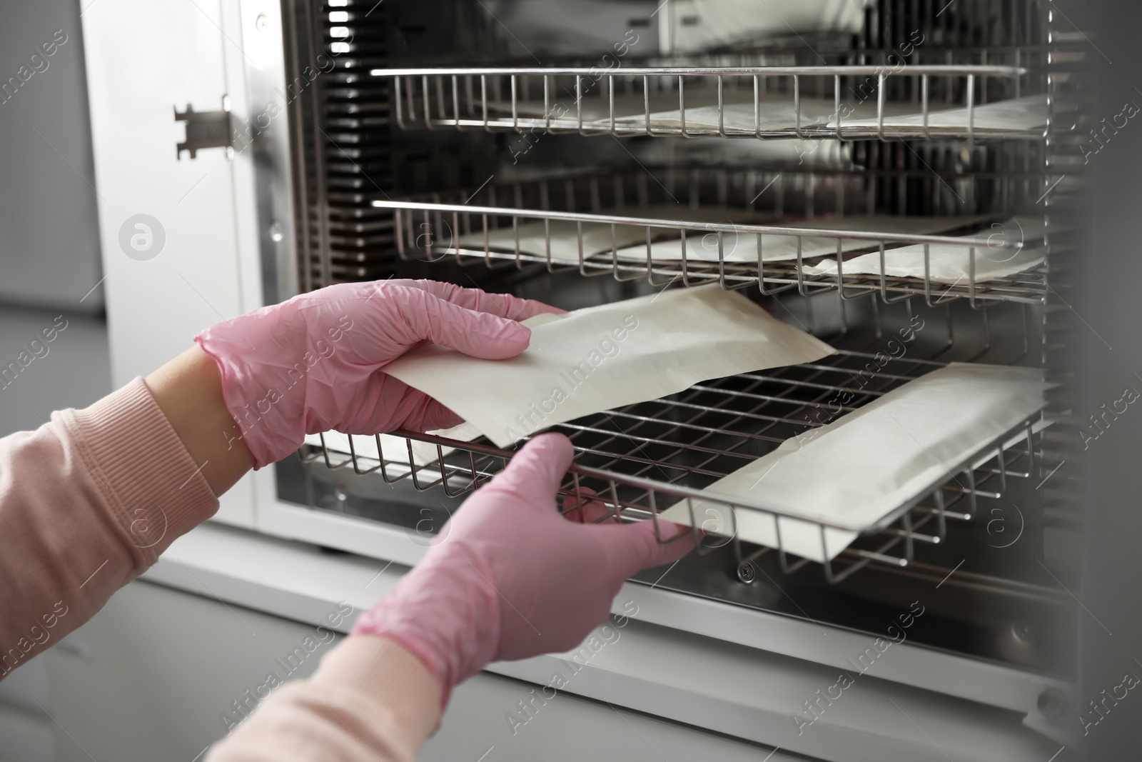 Photo of Professional manicurist putting tools into disinfection cabinet, closeup