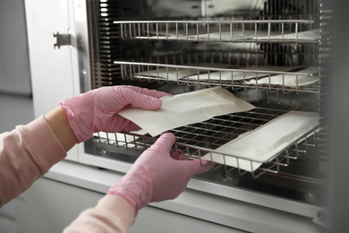 Photo of Professional manicurist putting tools into disinfection cabinet, closeup