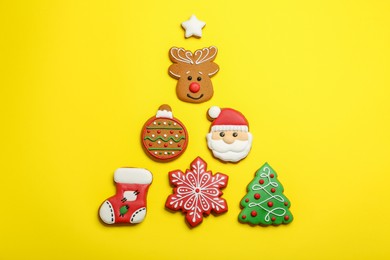 Different tasty Christmas cookies on yellow background, flat lay