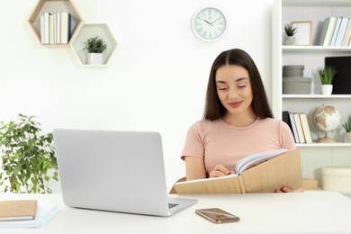 Home workplace. Woman writing in notebook at white desk in room