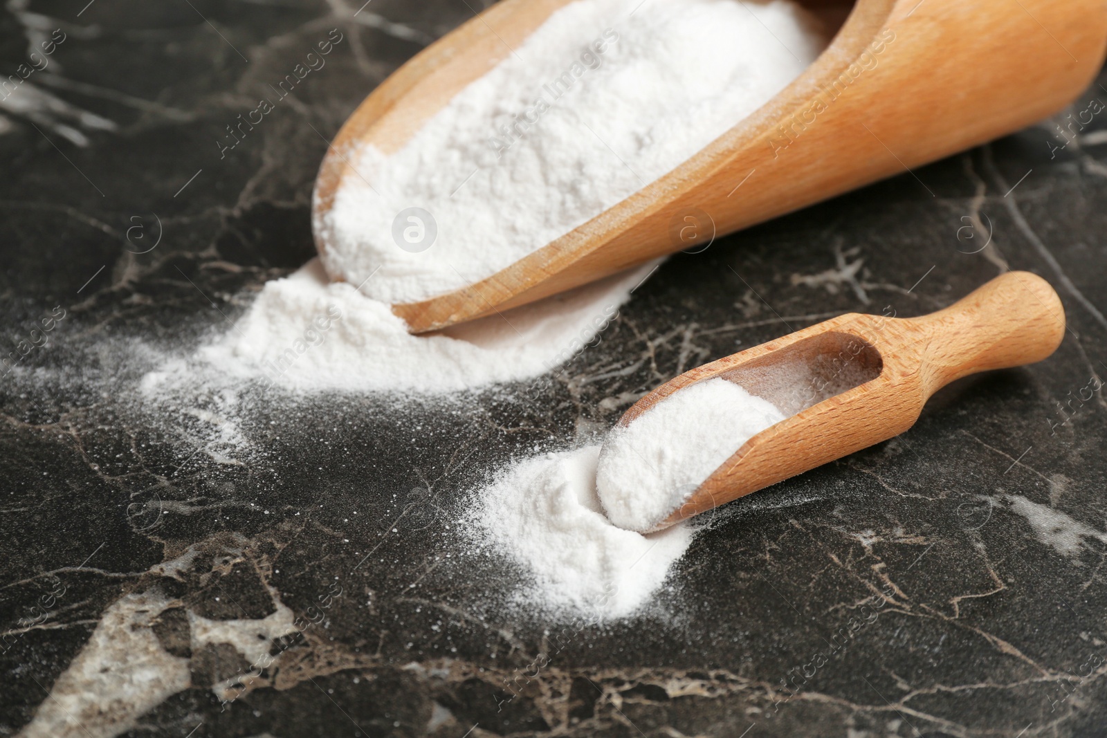 Photo of Scoops with baking soda on dark table