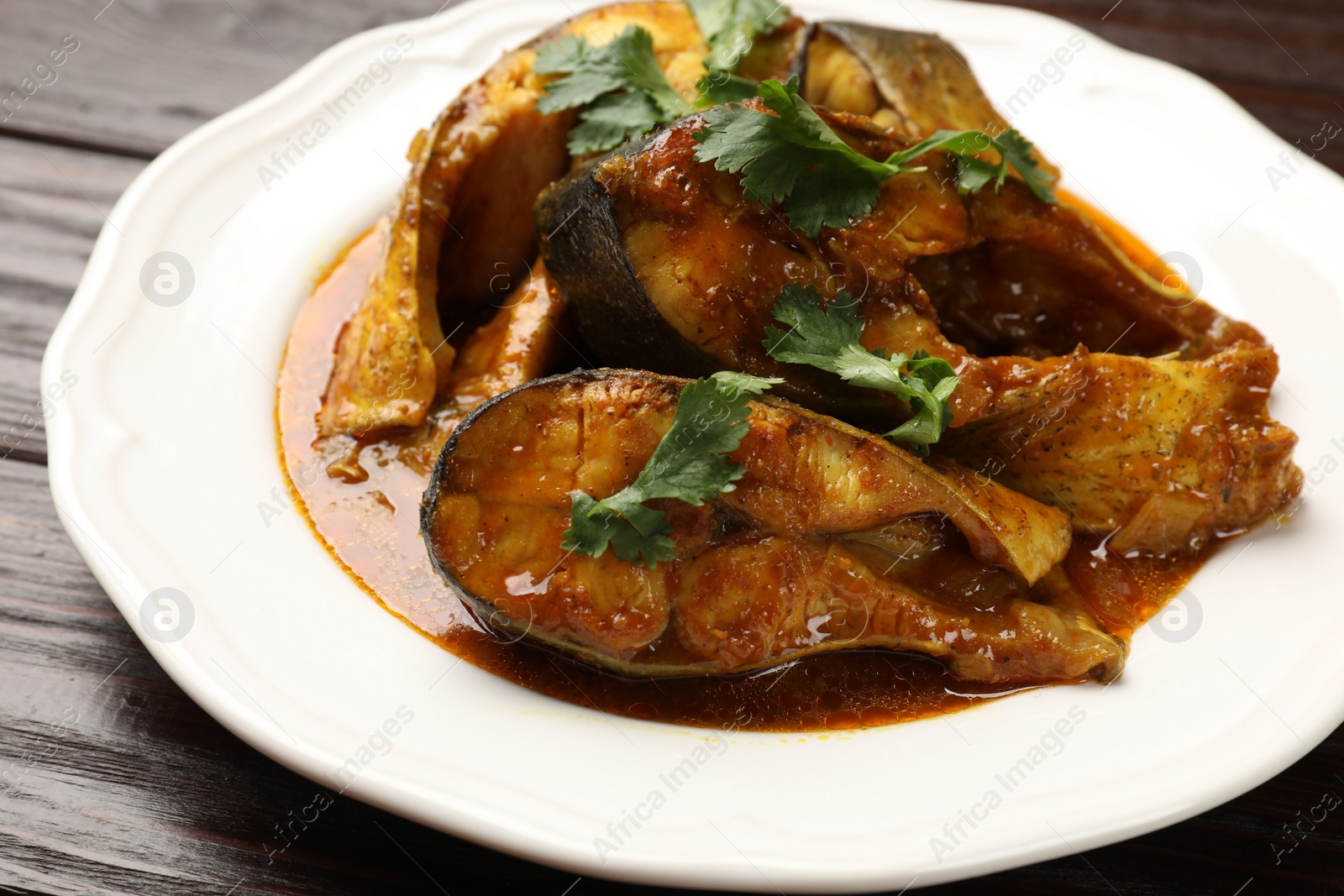 Photo of Tasty fish curry on wooden table, closeup. Indian cuisine