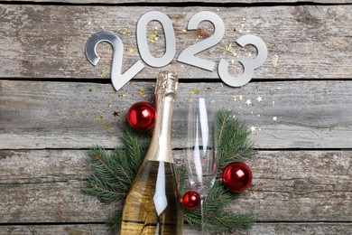 Photo of Happy New Year 2023! Flat lay composition with bottle of sparkling wine on wooden table