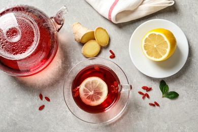 Photo of Flat lay composition with cup of healthy goji tea on grey table