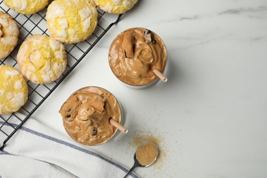 Photo of Glasses of delicious dalgona coffee with cookies on white marble table, flat lay. Space for text