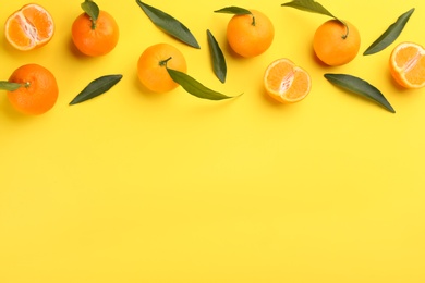 Photo of Fresh tangerines with green leaves on yellow background, flat lay. Space for text