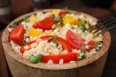 Photo of Cooked bulgur with vegetables in bowl on table, closeup