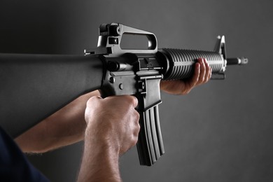 Assault gun. Man aiming rifle on dark background, closeup
