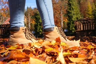 Woman standing on ground covered with fallen autumn leaves