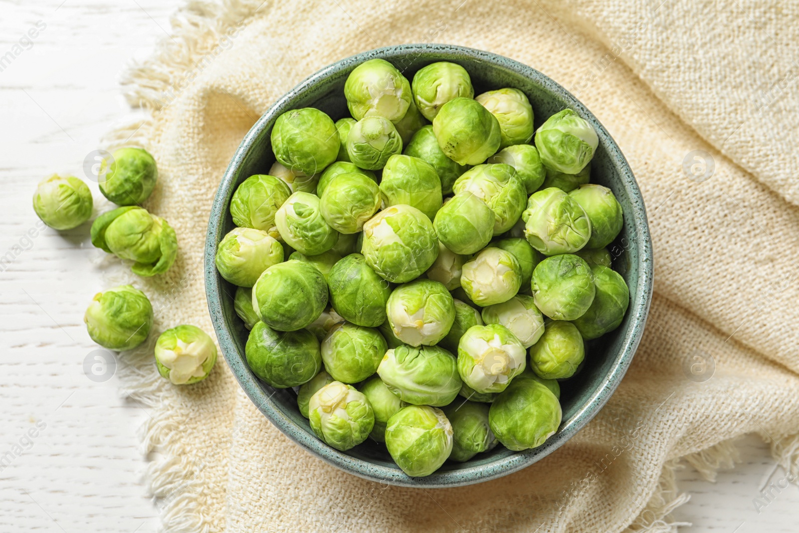 Photo of Bowl of fresh Brussels sprouts and napkin on wooden background, top view