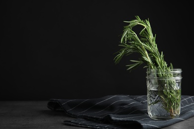 Photo of Fresh green rosemary in jar on table, space for text